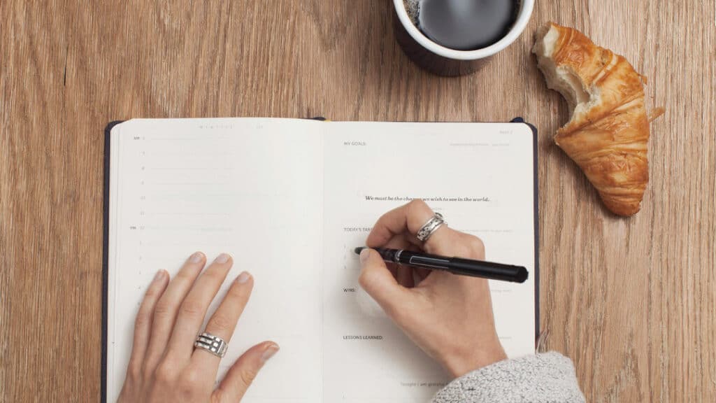 Eine Person schreibt Aufgaben in ein Notizbuch